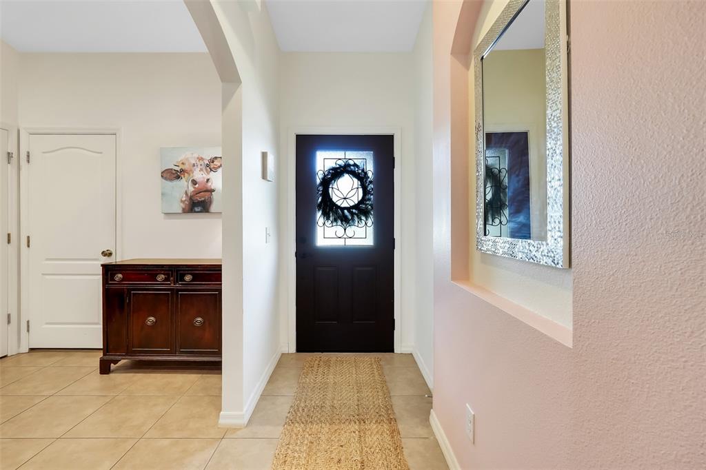 An entryway features a dark front door with a wreath, tile flooring, and a wooden cabinet — 732 ARBOR POINTE AVENUE, MINNEOLA, FL