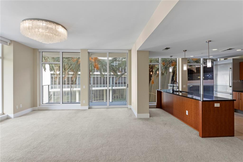 An open-concept living area features beige carpeting, a kitchen island, and floor-to-ceiling windows — 175 1ST STREET S UNIT 303, ST PETERSBURG, FL