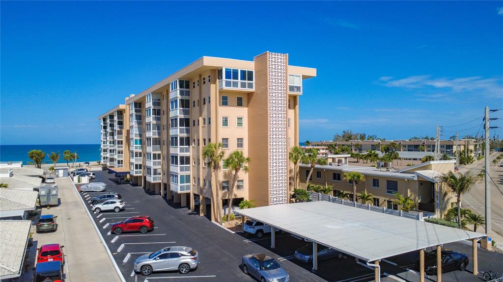 An aerial view shows a multi-story apartment building with a parking lot and carport — 1255 TARPON CENTER DRIVE UNIT 510, VENICE, FL