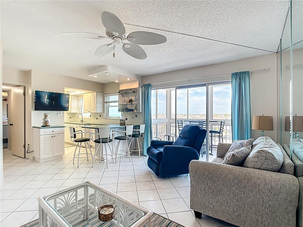A living room with tile floors, a ceiling fan, a kitchen island, and balcony access — 1255 TARPON CENTER DRIVE UNIT 510, VENICE, FL