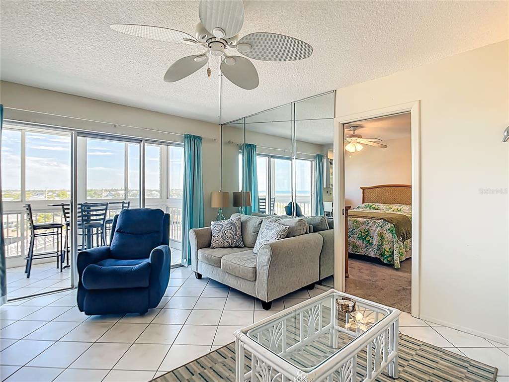 A living room with tile floors, a blue recliner, a sofa, and a mirrored wall — 1255 TARPON CENTER DRIVE UNIT 510, VENICE, FL