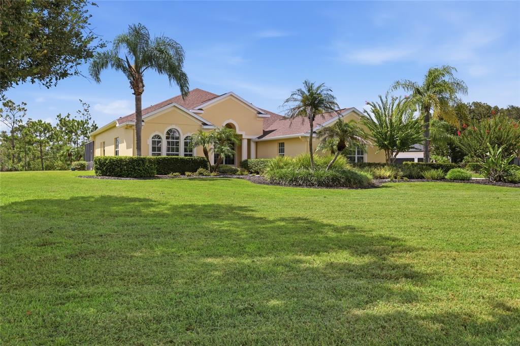 A yellow single-story house with a large front lawn and several palm trees — 23327 RED ROBIN PLACE, BRADENTON, FL