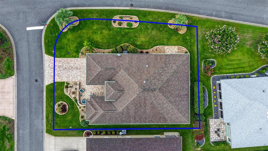 An aerial view shows a single-story house with a paved driveway and landscaped yard — 2947 RAIN LILY LOOP, THE VILLAGES, FL