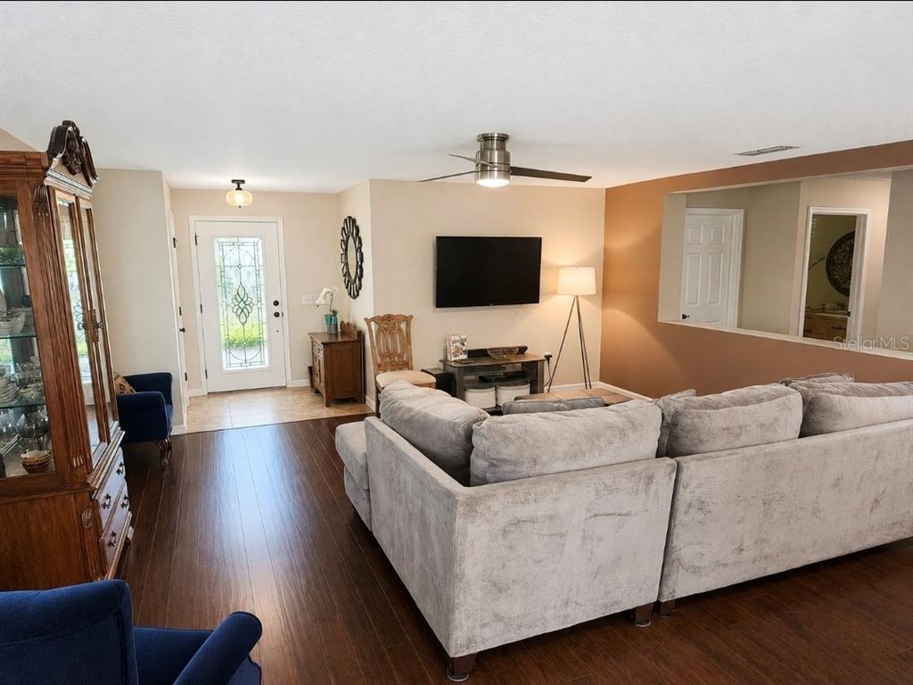 A living room features dark wood floors, a gray sectional sofa, and a wall-mounted television — 32 ANGELA DRIVE, PALM COAST, FL