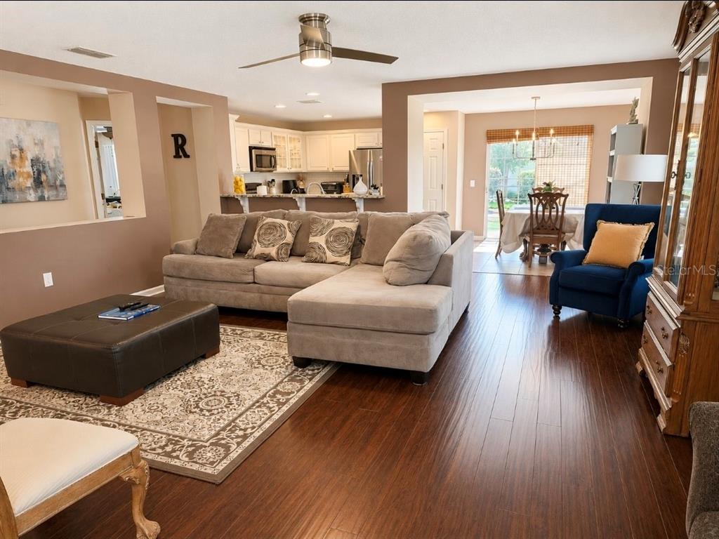 A living room with a sectional sofa, dark wood floors, and an open kitchen view — 32 ANGELA DRIVE, PALM COAST, FL