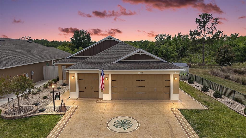 An exterior view of a single-story house with a three-car garage and a paved driveway — 4044 MAXWELL TERRACE, THE VILLAGES, FL