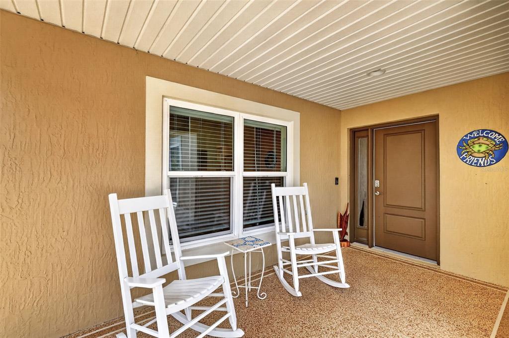 A covered front porch features two white rocking chairs, a small side table, and a door — 4044 MAXWELL TERRACE, THE VILLAGES, FL