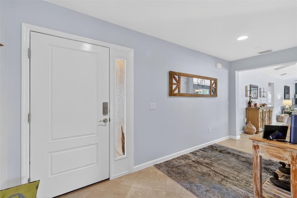 An entryway features a white front door with a sidelight, light blue walls, and tile flooring — 4044 MAXWELL TERRACE, THE VILLAGES, FL