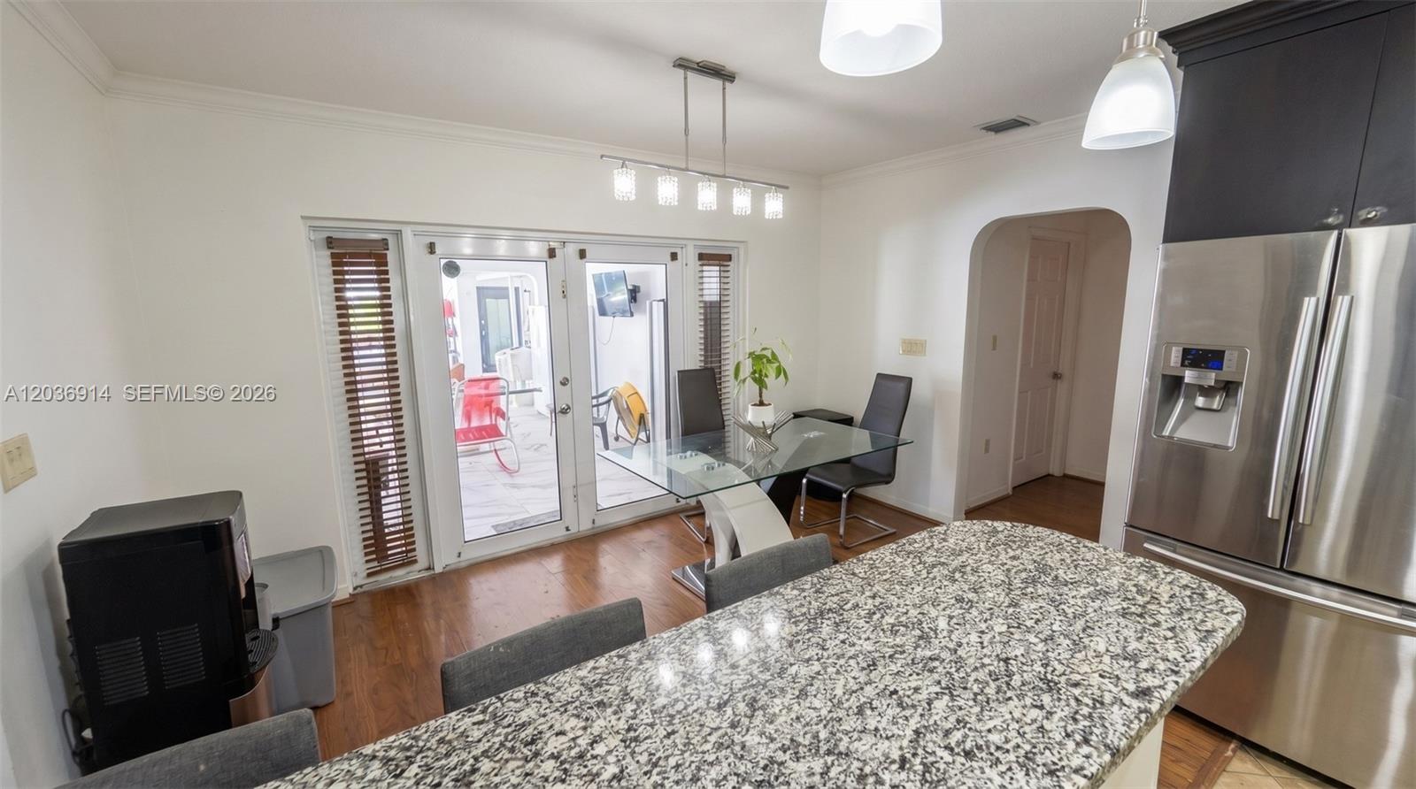 A kitchen and dining area features a granite island, glass table, and glass patio doors — MIAMI, FL