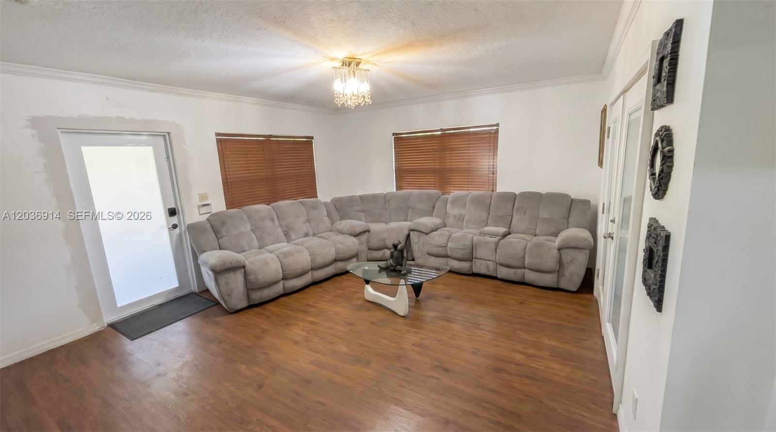 A living room features a large gray sectional sofa, wood flooring, and a glass table — MIAMI, FL
