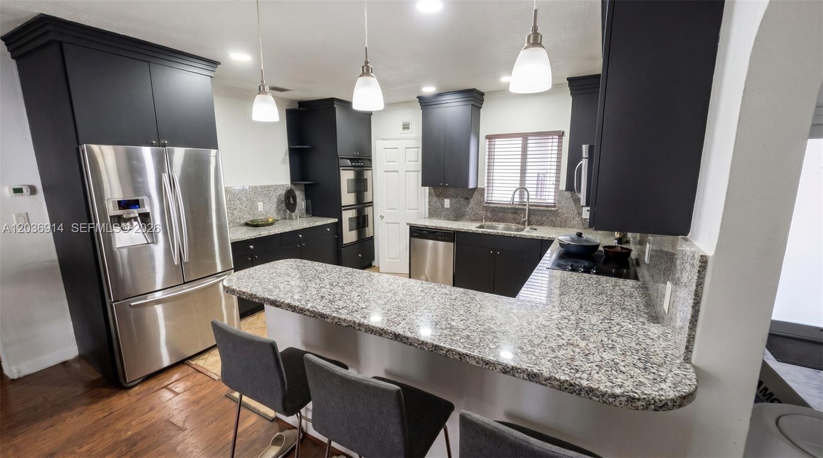 A kitchen features dark cabinets, granite countertops, stainless steel appliances, and a breakfast bar — MIAMI, FL