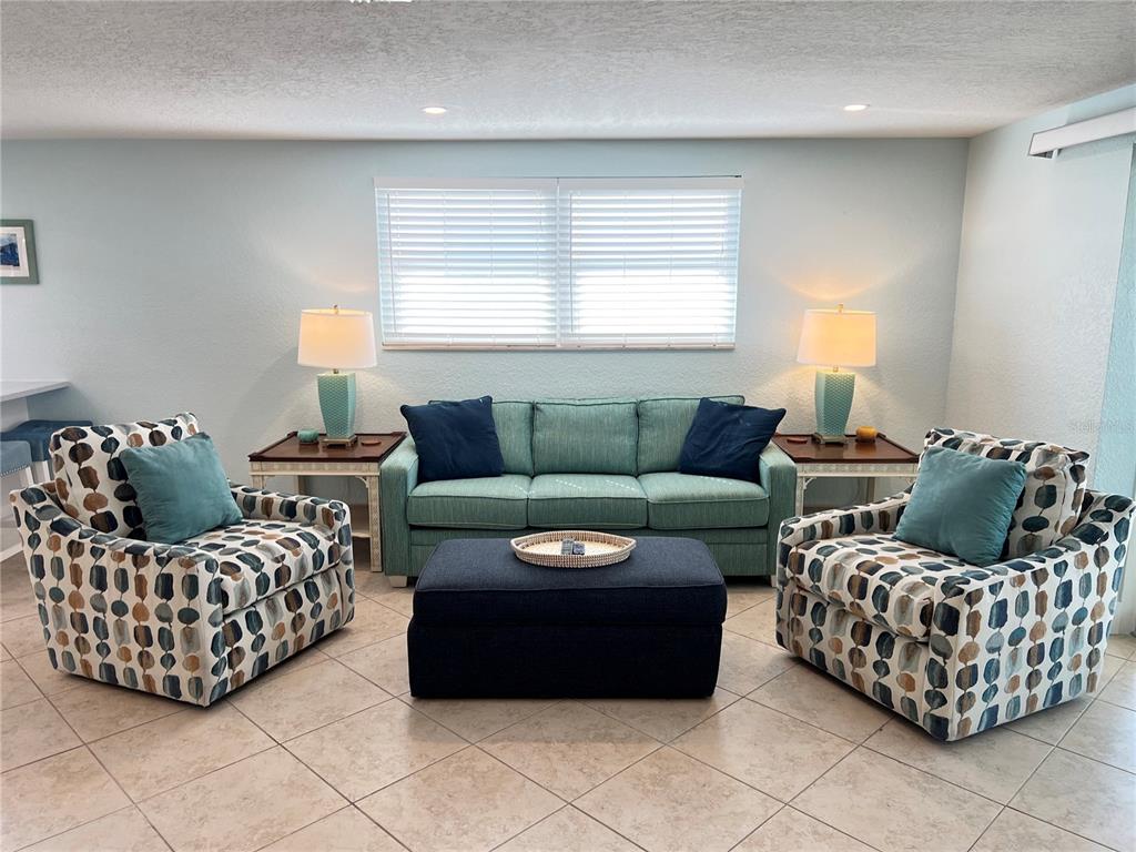 A living room features a teal sofa, two patterned armchairs, and a dark blue ottoman — 6154 MIDNIGHT PASS ROAD UNIT B11, SARASOTA, FL