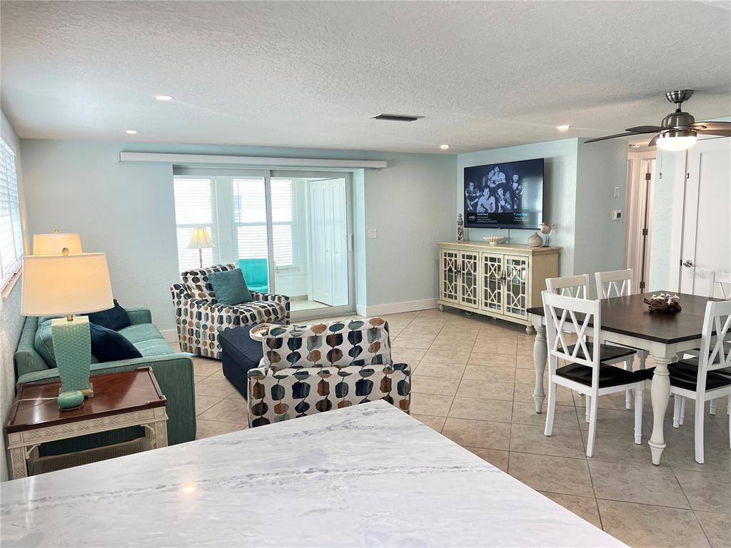 An open-concept living and dining area features light blue walls, tile flooring, and a ceiling fan — 6154 MIDNIGHT PASS ROAD UNIT B11, SARASOTA, FL