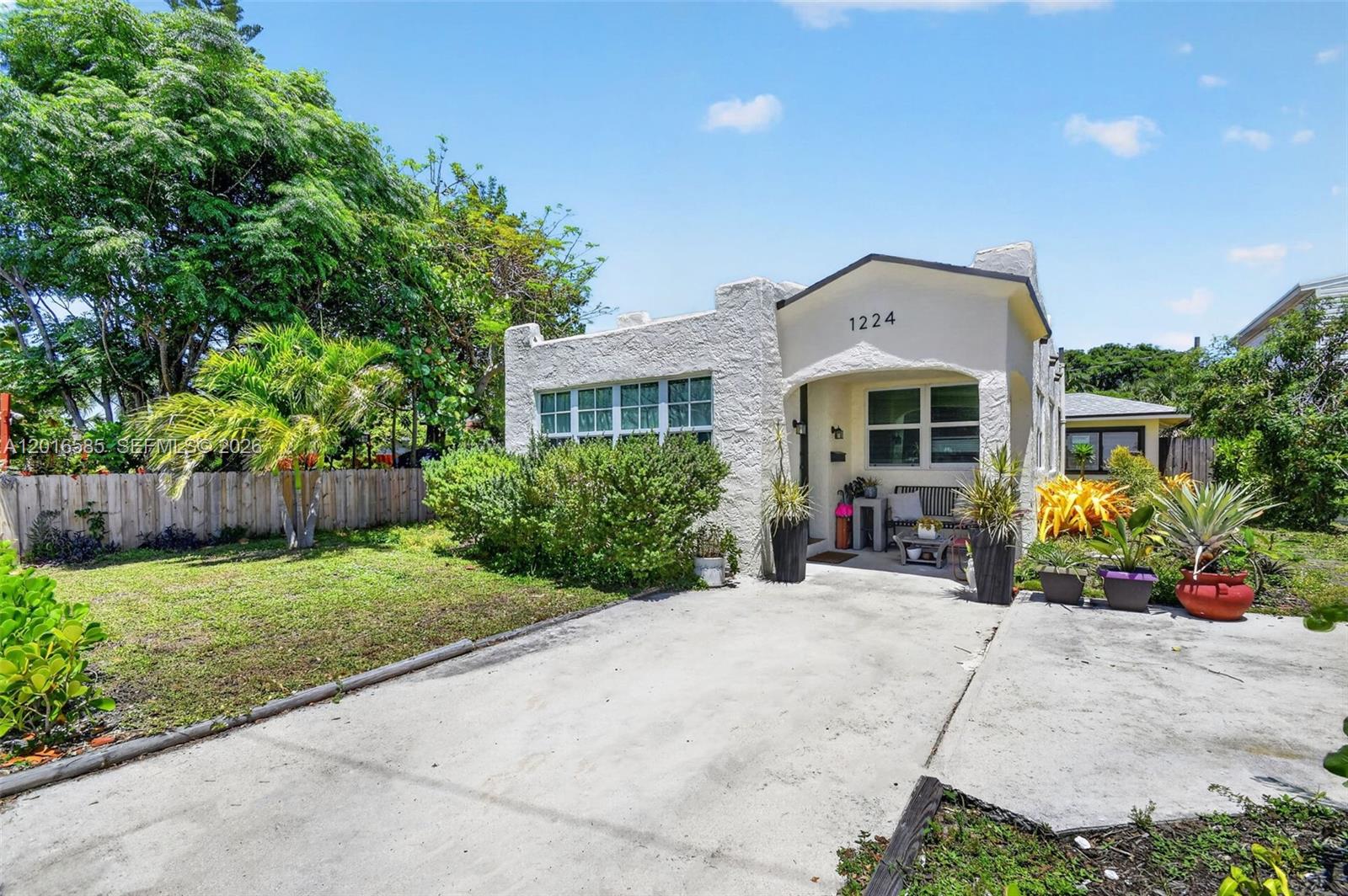 A single-story stucco house with a front porch, driveway, and landscaped yard under a blue sky — 1224 N K St, Lake Worth FL 33460, LAKE WORTH, FL