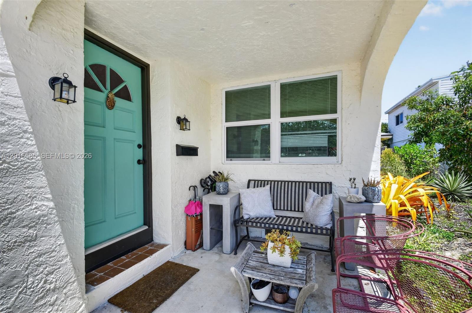 A covered front porch features a teal door, a metal bench, and potted plants — 1224 N K St, Lake Worth FL 33460, LAKE WORTH, FL