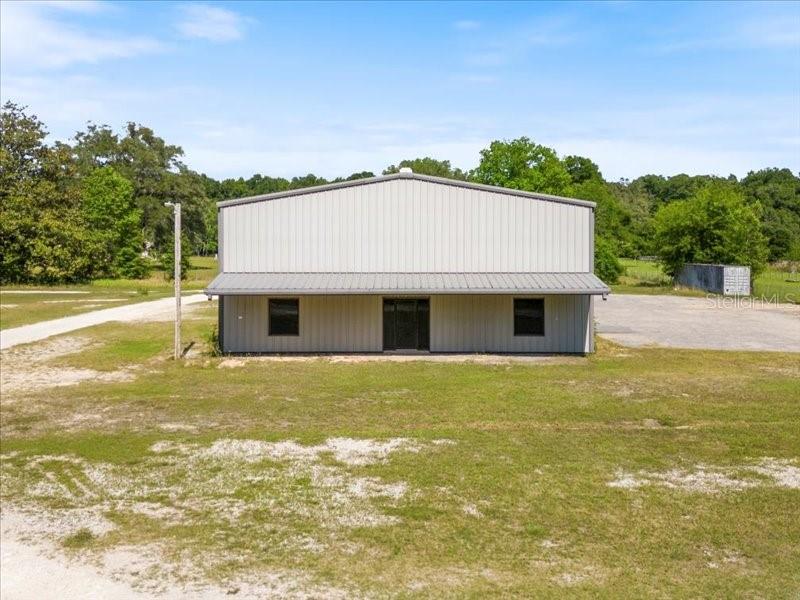 A metal-sided warehouse building stands on a large, grassy lot under a blue sky — 22429 S US HIGHWAY 441, HIGH SPRINGS, FL