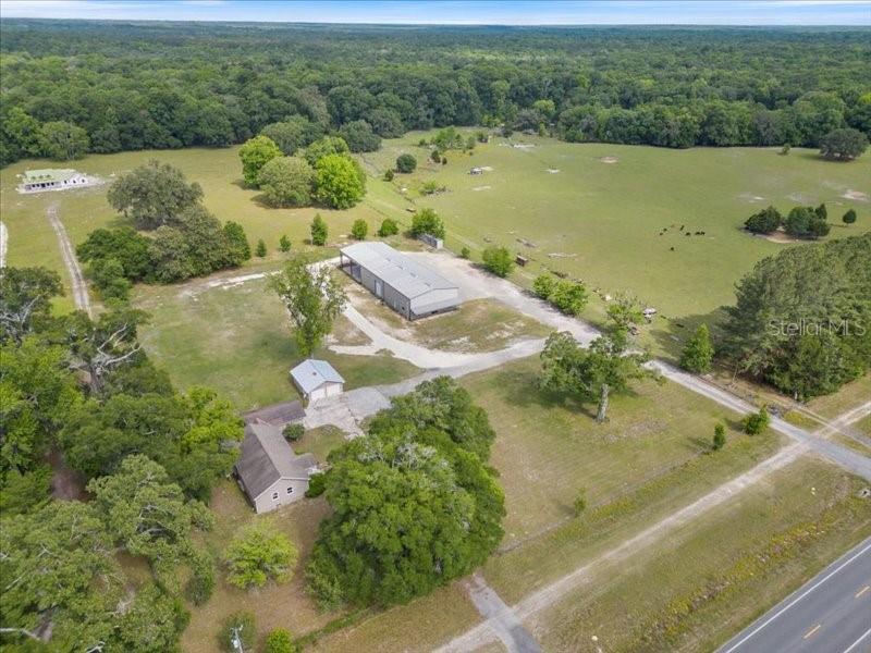 An aerial view shows a rural property with a house, a large metal building, and pasture — 22429 S US HIGHWAY 441, HIGH SPRINGS, FL