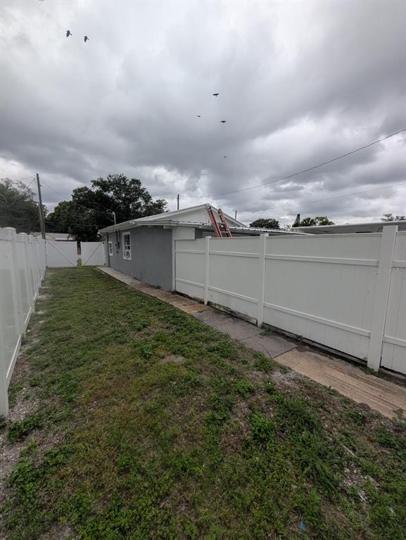 A narrow side yard features a gray house exterior, a white vinyl fence, and grass — 793 ELDRIDGE STREET, ORLANDO, FL