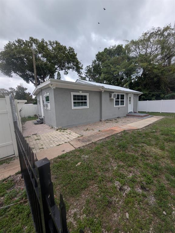 The exterior of a gray stucco house features a paved patio and a white fence — 793 ELDRIDGE STREET, ORLANDO, FL