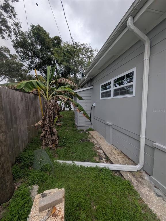 A side view of a gray house exterior featuring a white downspout and banana trees — 793 ELDRIDGE STREET, ORLANDO, FL