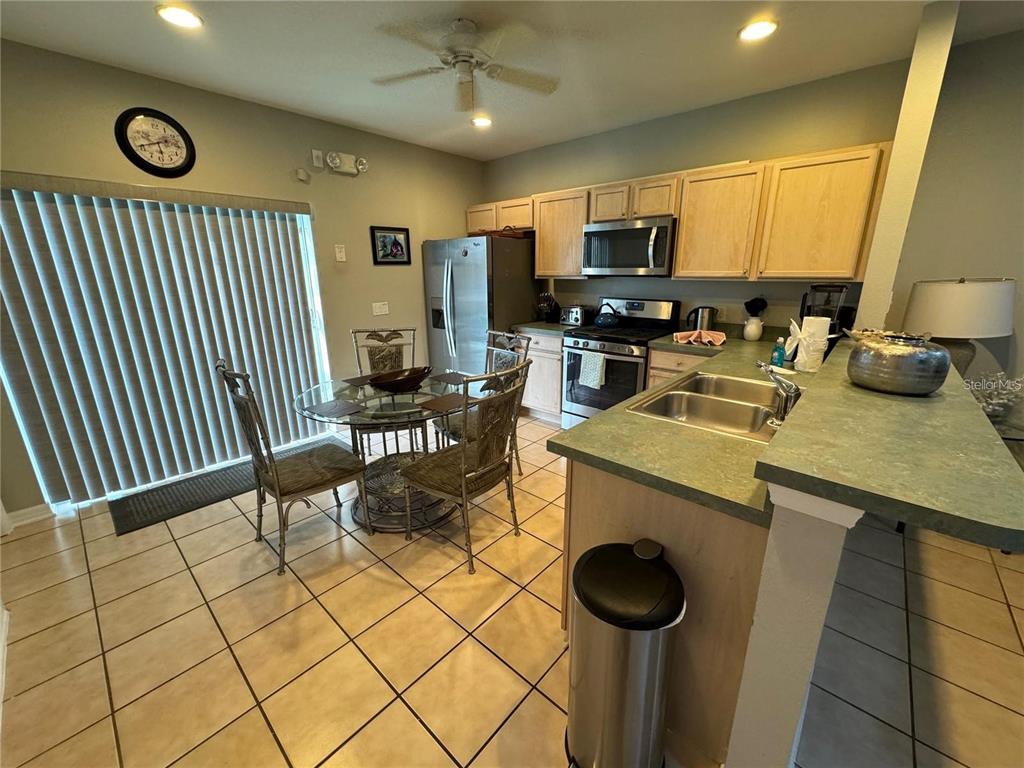 A kitchen and dining area with light wood cabinets, green countertops, and tile flooring — 702 SONJA CIRCLE, DAVENPORT, FL