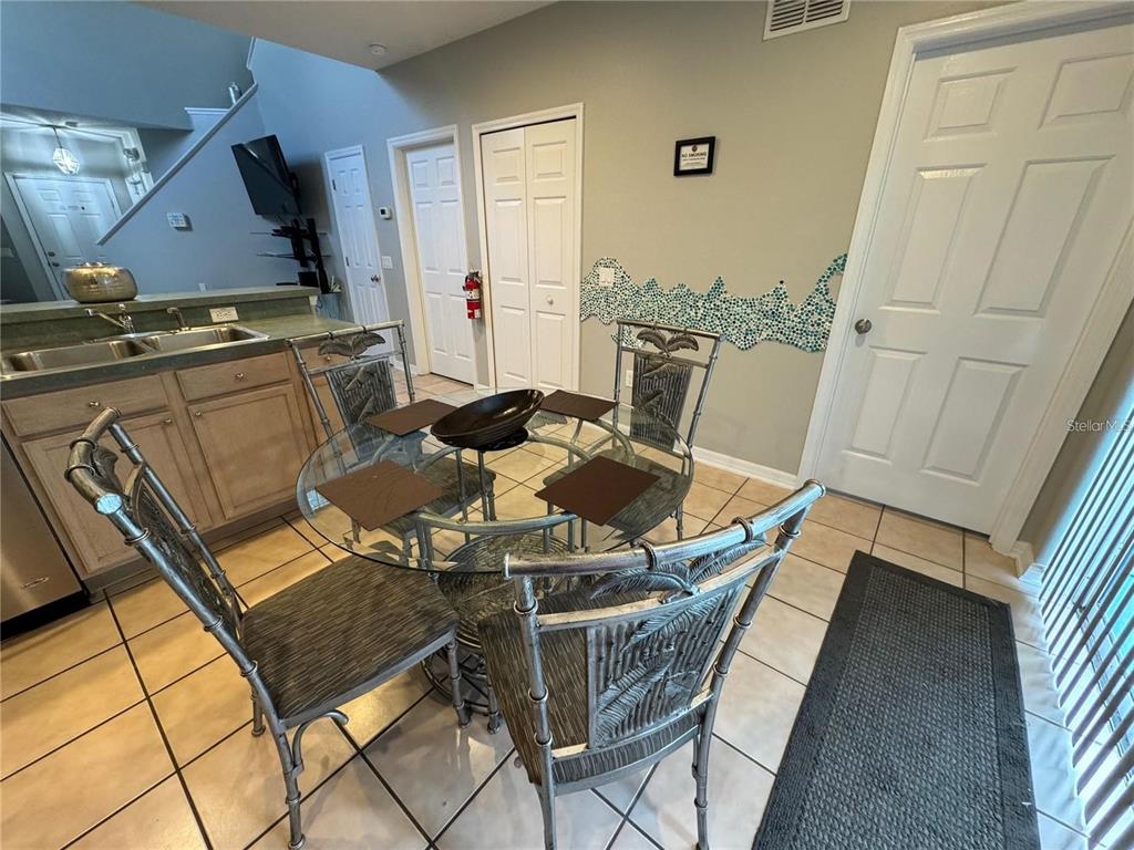 A dining area features a glass-topped table with four metal chairs on a tiled floor — 702 SONJA CIRCLE, DAVENPORT, FL