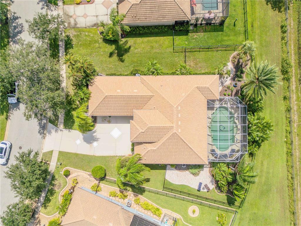 An aerial view shows a house with a tiled roof, a screened pool, and landscaping — 3604 MARIBELLA DRIVE, NEW SMYRNA BEACH, FL
