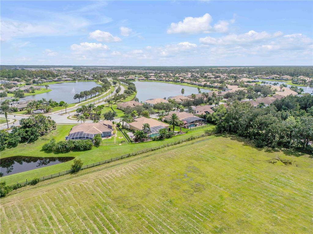 An aerial view shows a residential neighborhood with houses, swimming pools, and a large lake — 3604 MARIBELLA DRIVE, NEW SMYRNA BEACH, FL