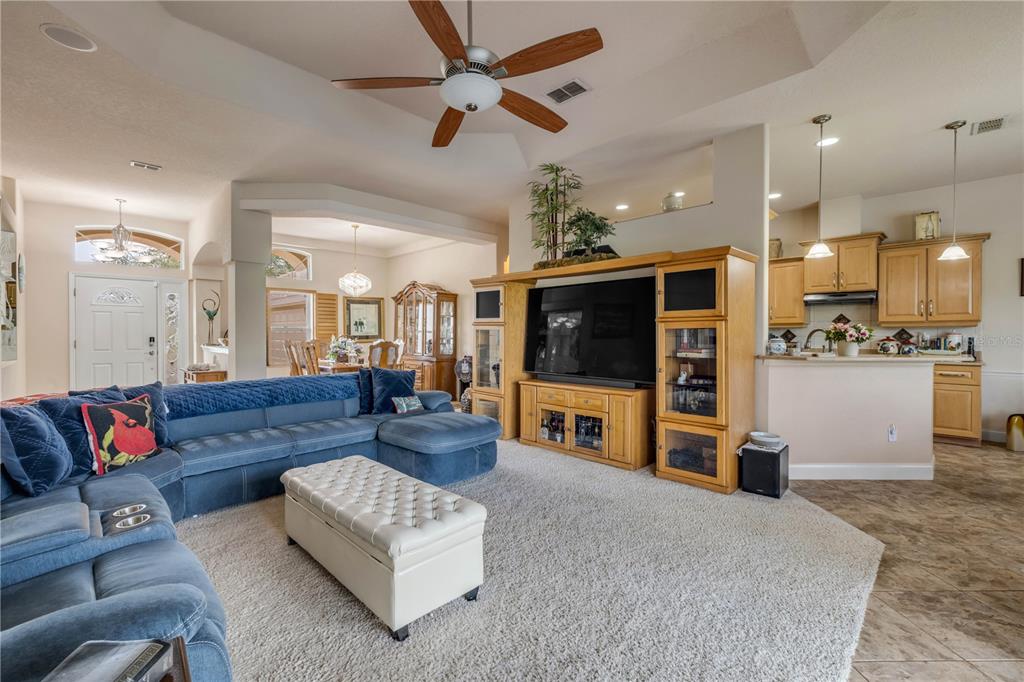 A living room features a blue sectional sofa, a white ottoman, and a wooden entertainment center — 3604 MARIBELLA DRIVE, NEW SMYRNA BEACH, FL