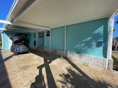 A teal mobile home features a covered carport with a patterned concrete driveway and golf cart — 4851 W GANDY BOULEVARD UNIT 5C, TAMPA, FL