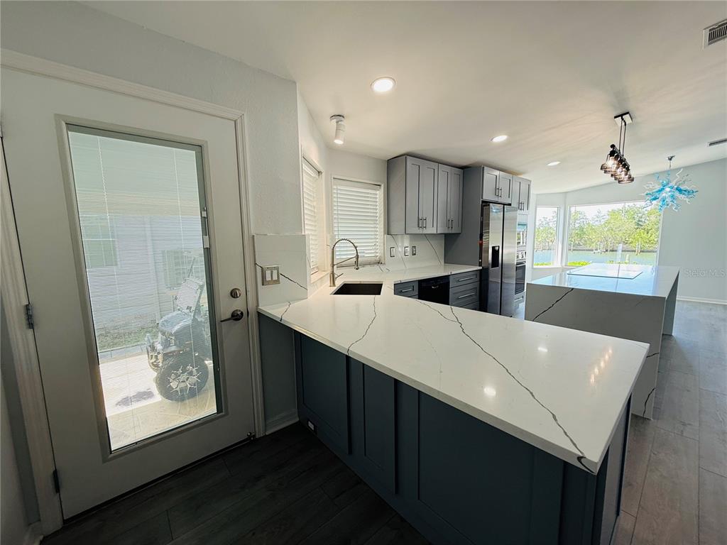 A kitchen features blue cabinets, white quartz countertops, and a view of a golf cart — 4851 W GANDY BOULEVARD UNIT 5C, TAMPA, FL