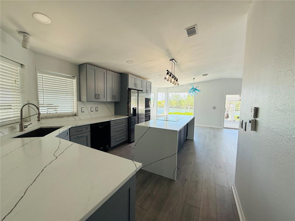 A modern kitchen features gray cabinets, white marble-patterned countertops, and a large central island — 4851 W GANDY BOULEVARD UNIT 5C, TAMPA, FL