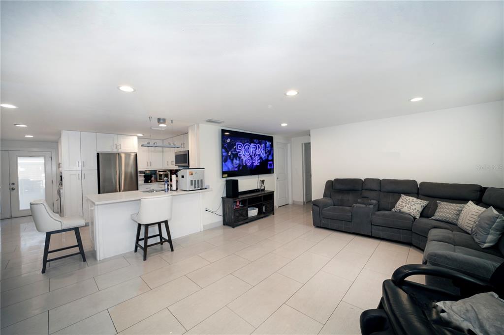 An open-concept living room and kitchen featuring white cabinetry, a breakfast bar, and gray seating — 2653 22ND STREET, SARASOTA, FL