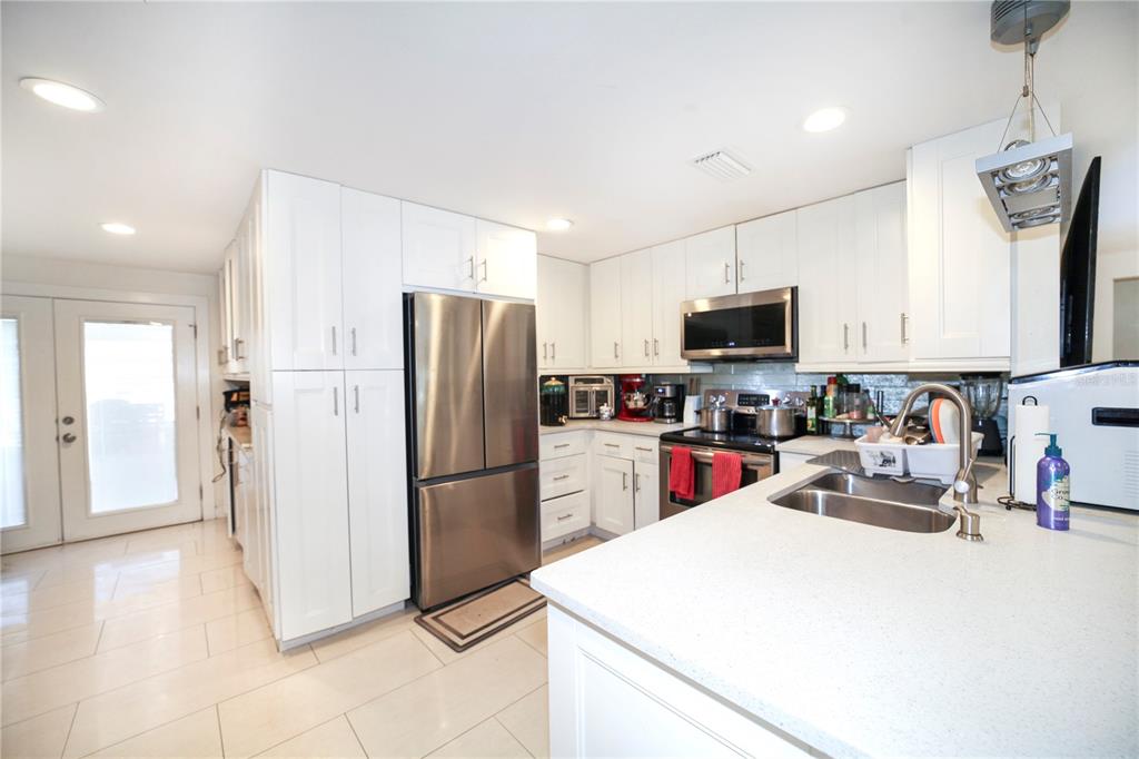 A kitchen features white cabinetry, stainless steel appliances, a quartz countertop, and light tile flooring — 2653 22ND STREET, SARASOTA, FL