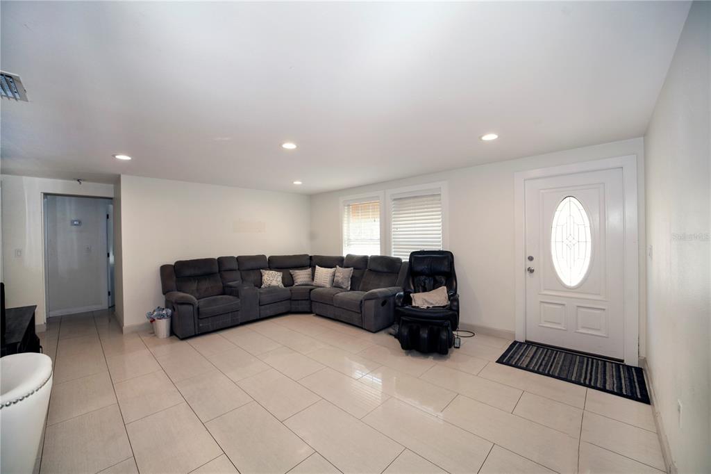 A living room features light tile flooring, a gray sectional sofa, and a white front door — 2653 22ND STREET, SARASOTA, FL