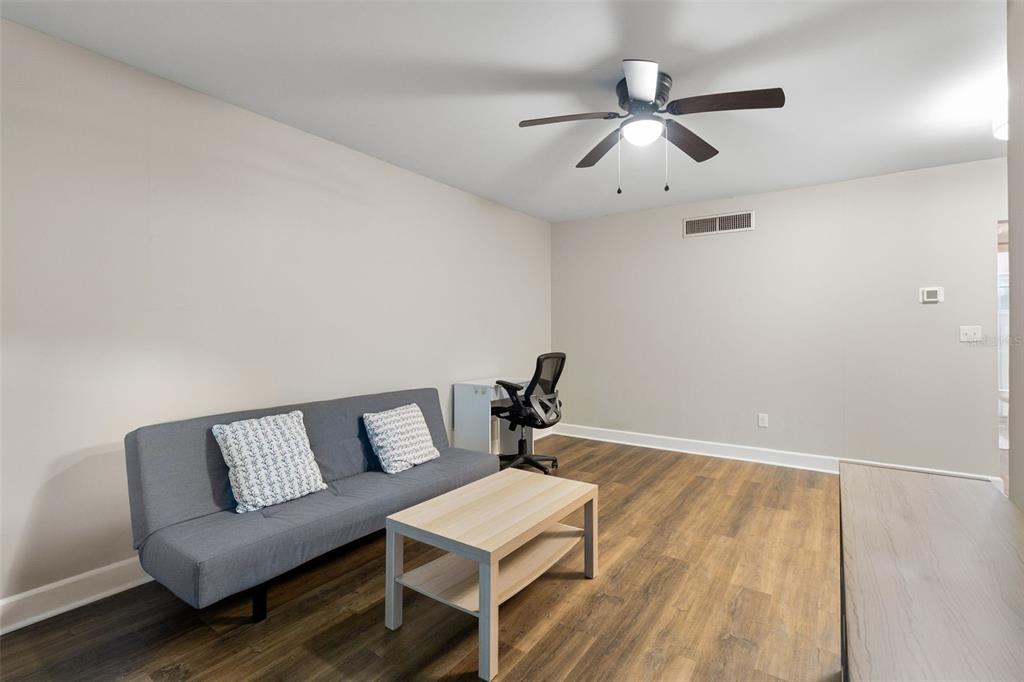 A living room features wood-look flooring, a ceiling fan, a sofa, and a storage unit — 1140 S ORLANDO AVENUE UNIT E11, MAITLAND, FL