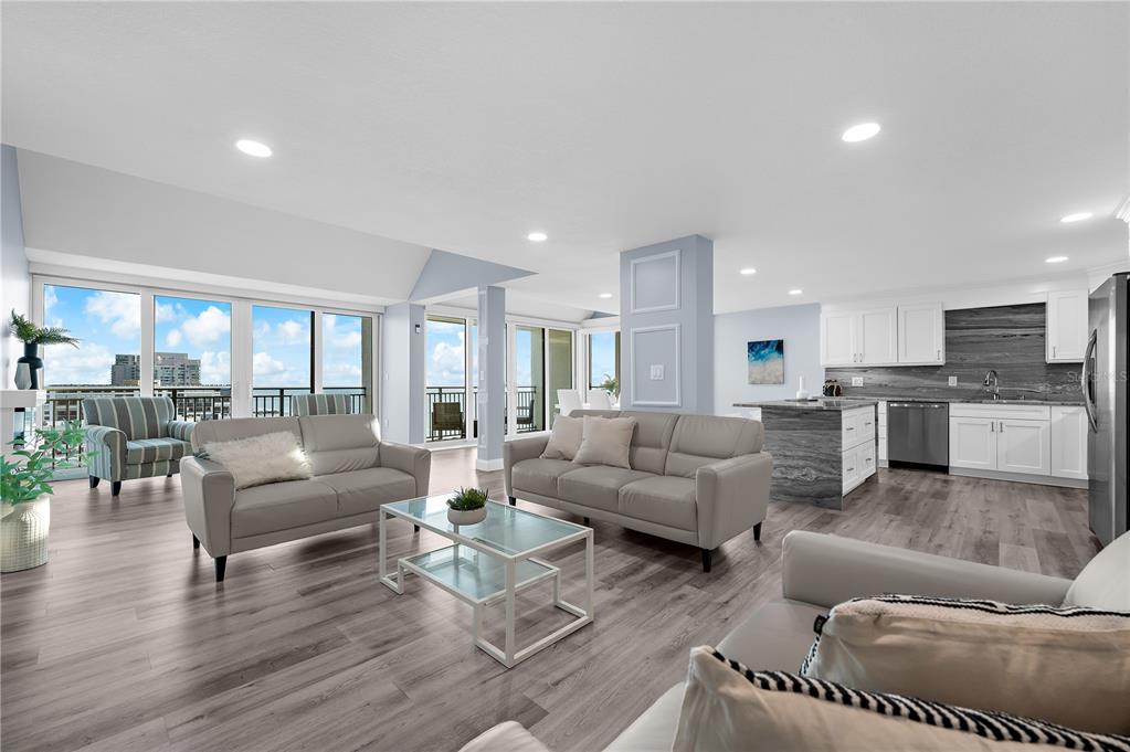 An open-concept living room and kitchen with gray wood-look flooring and floor-to-ceiling windows — 1380 GULF BOULEVARD UNIT PH 5, CLEARWATER BEACH, FL