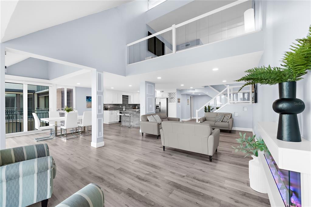 An open-concept living and dining area features light wood flooring, white cabinetry, and vaulted ceilings — 1380 GULF BOULEVARD UNIT PH 5, CLEARWATER BEACH, FL