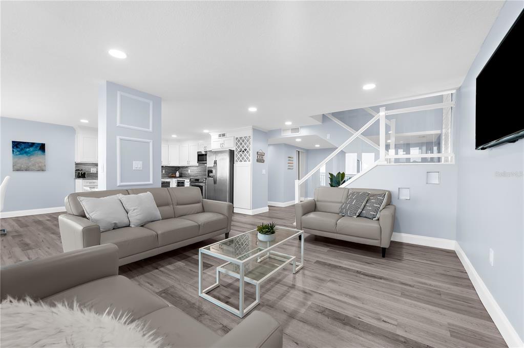 A living room with gray leather sofas, a glass coffee table, and an open kitchen — 1380 GULF BOULEVARD UNIT PH 5, CLEARWATER BEACH, FL
