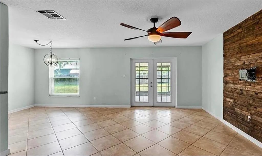 A living room with tile flooring, a ceiling fan, French doors, and a wood-paneled wall — 120 BENT OAK COURT, SANFORD, FL