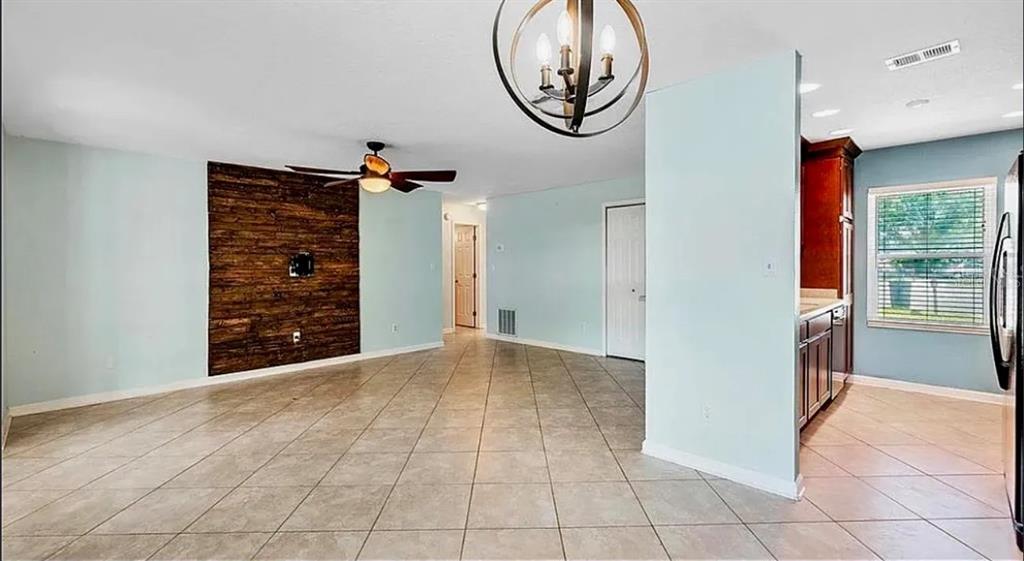 A living room with tile floors, a wood accent wall, and an open kitchen area — 120 BENT OAK COURT, SANFORD, FL