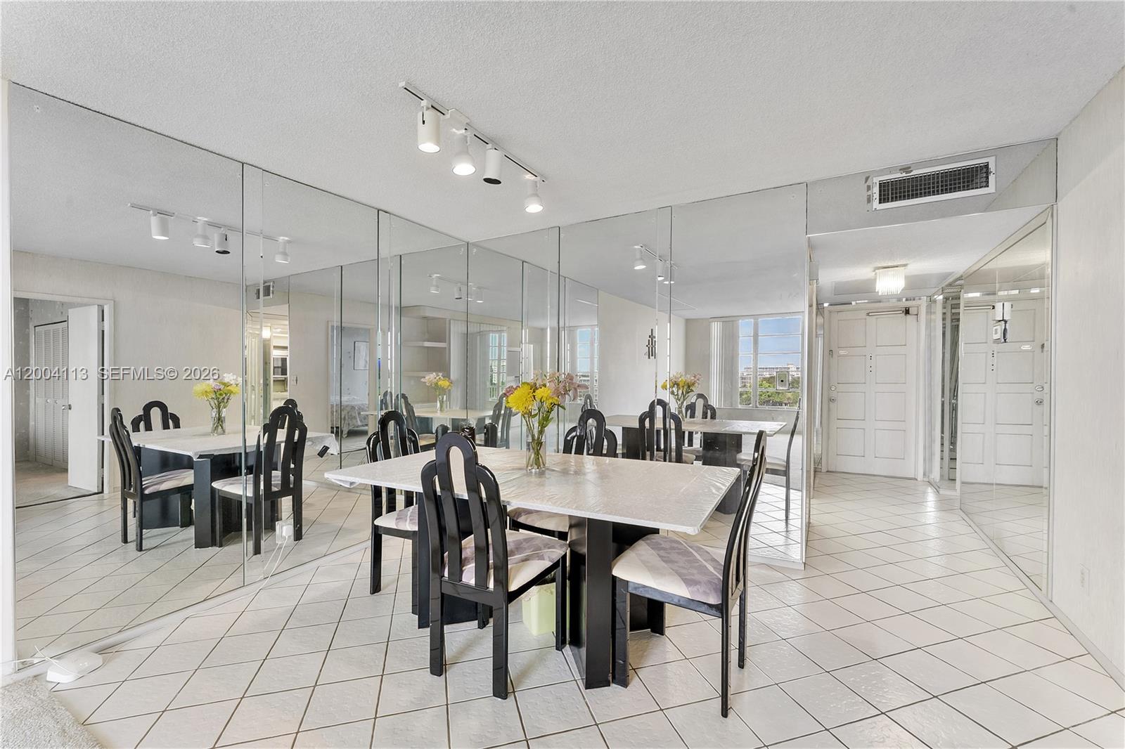 A dining room features a table with black chairs, tiled floors, and mirrored walls — 2661 S Course Dr # 805, Pompano Beach FL 33069, POMPANO BEACH, FL