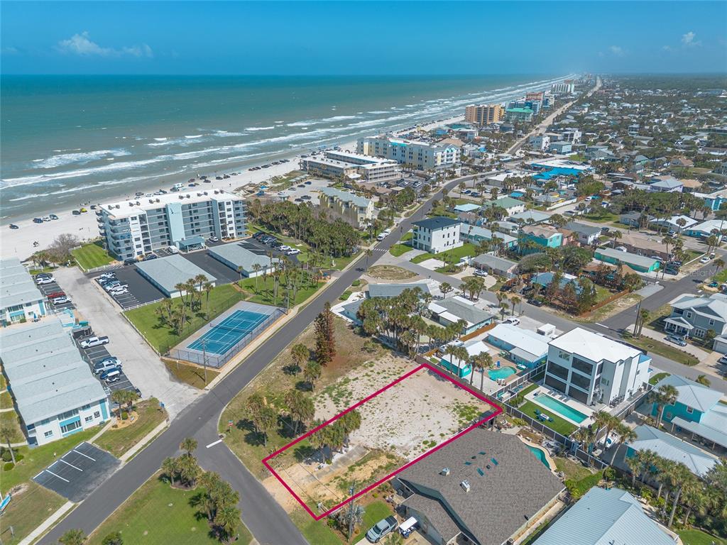 An aerial view shows a vacant rectangular lot outlined in pink near a beach — 0 DUE EAST STREET, NEW SMYRNA BEACH, FL
