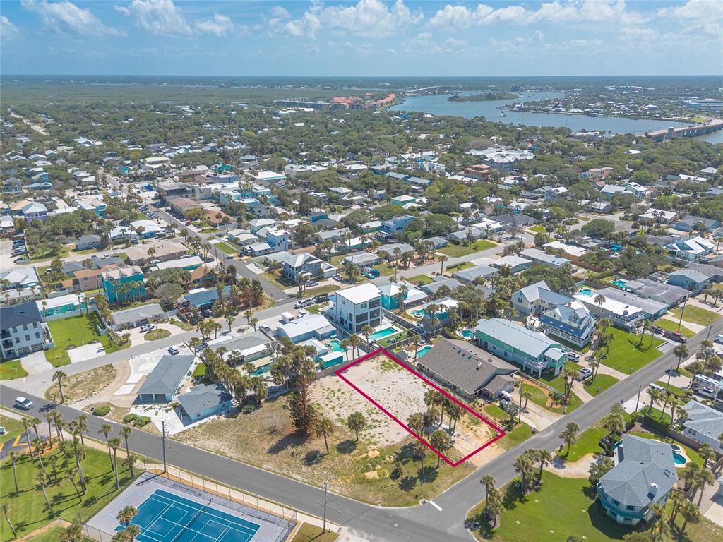 An aerial view shows a vacant rectangular lot outlined in pink near a tennis court — 0 DUE EAST STREET, NEW SMYRNA BEACH, FL