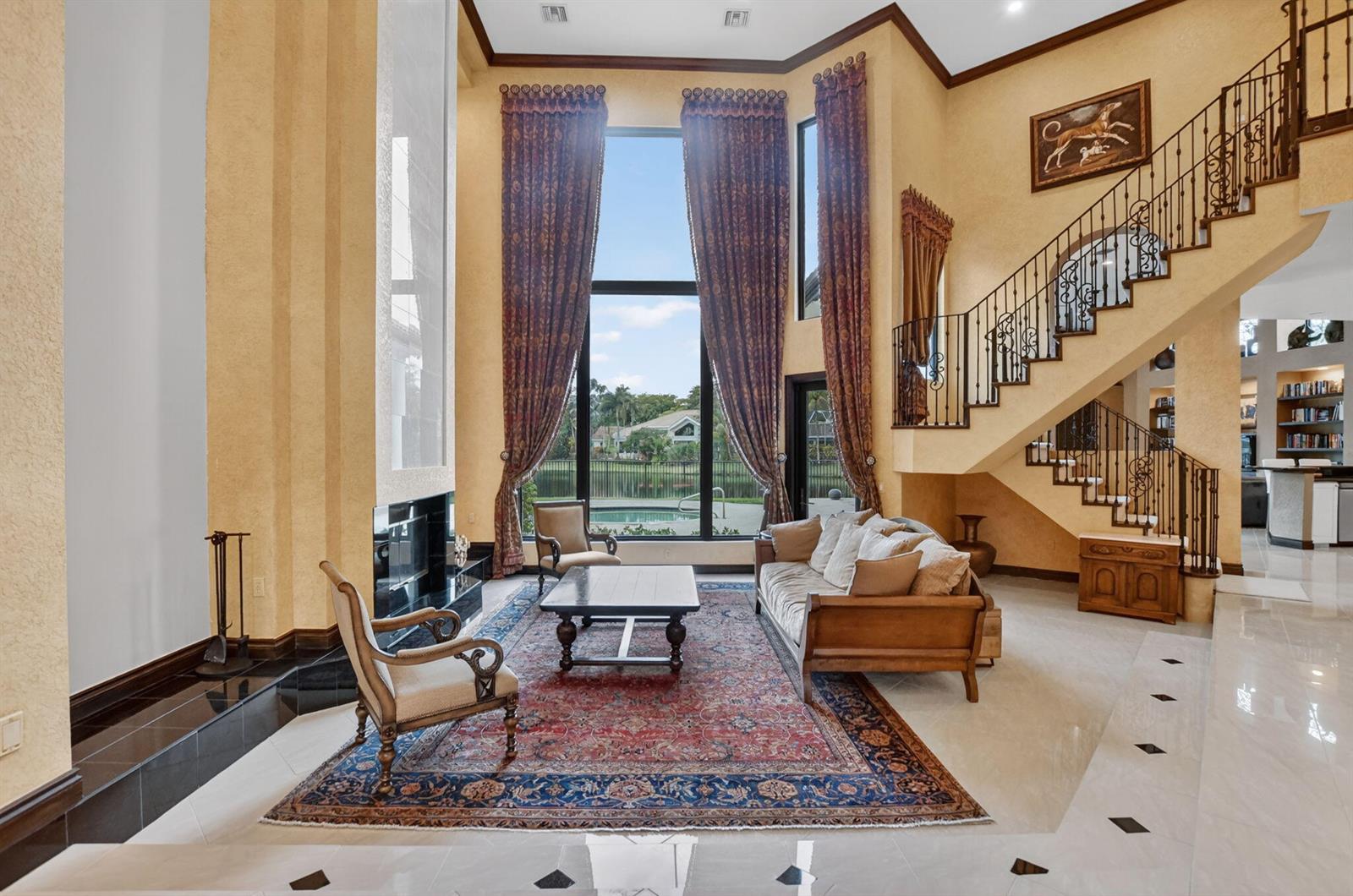 A two-story living room features a fireplace, tall windows, a staircase, and a patterned rug — 19220 Fox Landing Drive, Boca Raton FL 33434, BOCA RATON, FL
