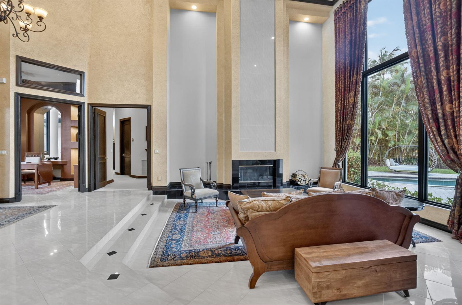 A spacious living room features high ceilings, a fireplace, tile floors, and large windows — 19220 Fox Landing Drive, Boca Raton FL 33434, BOCA RATON, FL