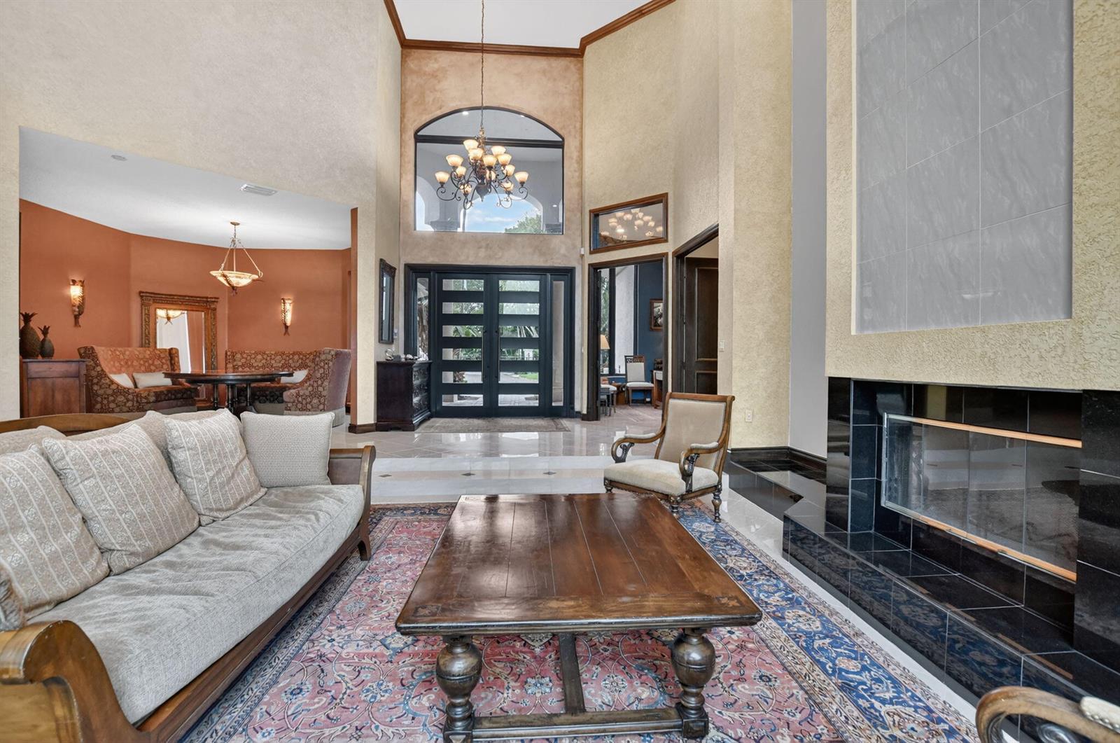 A living room with a high ceiling, fireplace, and a view of the front entryway — 19220 Fox Landing Drive, Boca Raton FL 33434, BOCA RATON, FL
