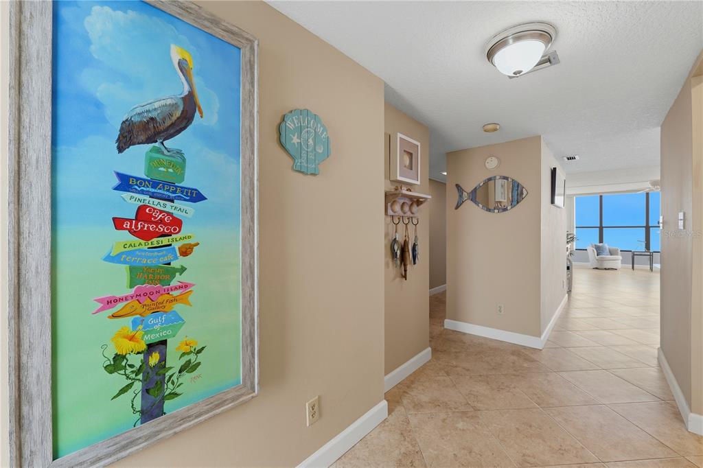 A hallway with tile flooring leads to a bright living area with floor-to-ceiling windows — 300 WOODETTE DRIVE UNIT 602, DUNEDIN, FL