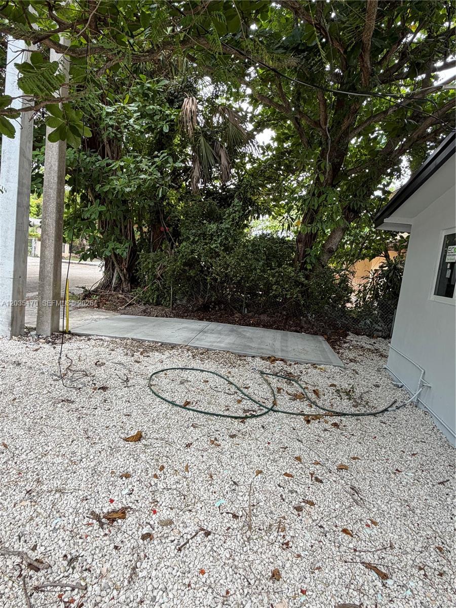 A concrete pad sits on a gravel yard next to a building and trees — 3220 Plaza St # 3220, Miami FL 33133, MIAMI, FL