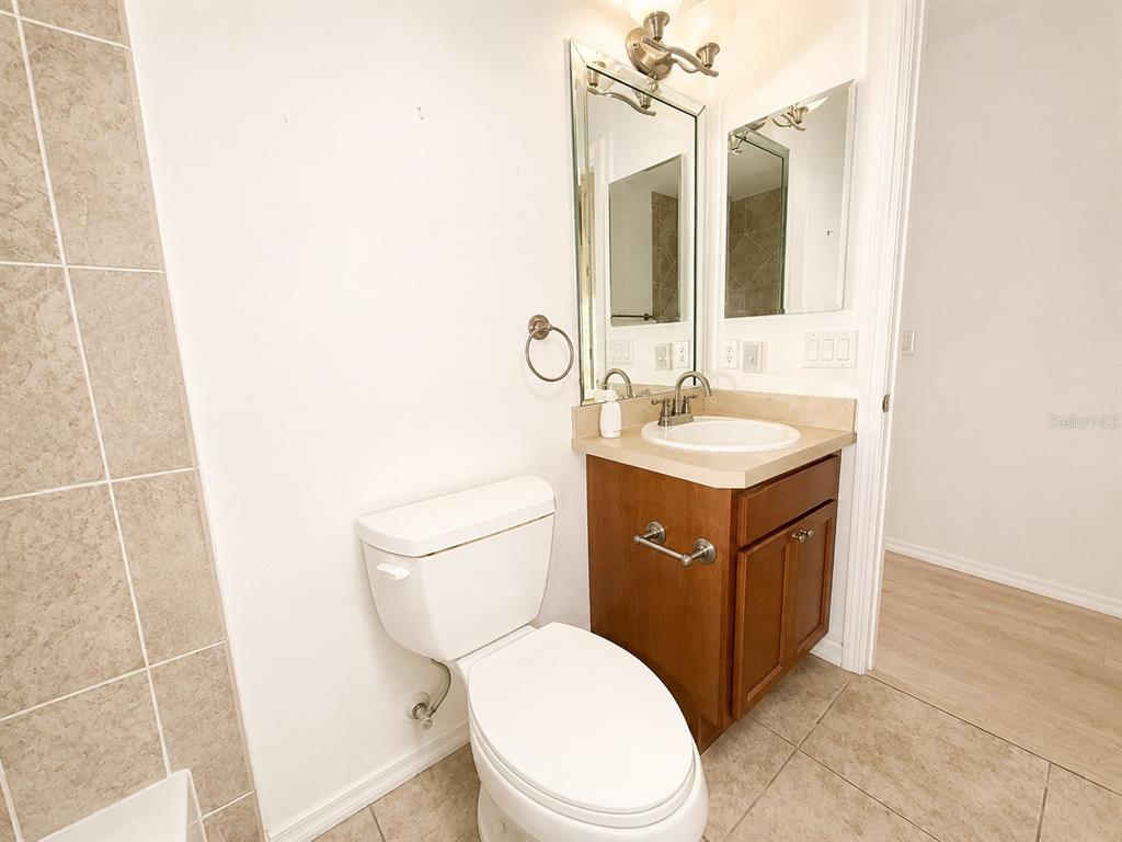 A bathroom features a white toilet, a wood vanity with a sink, and tiled flooring — 2251 EDMONTON PLACE, THE VILLAGES, FL
